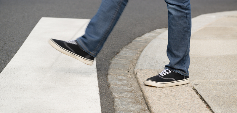 Feet of pedestrian stepping into crosswalk