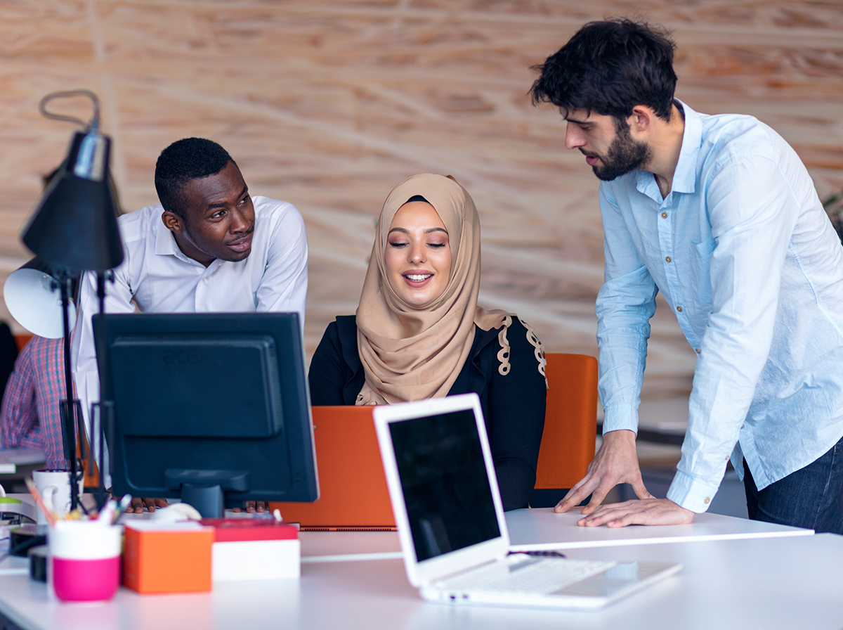 Three employees talking at a computer