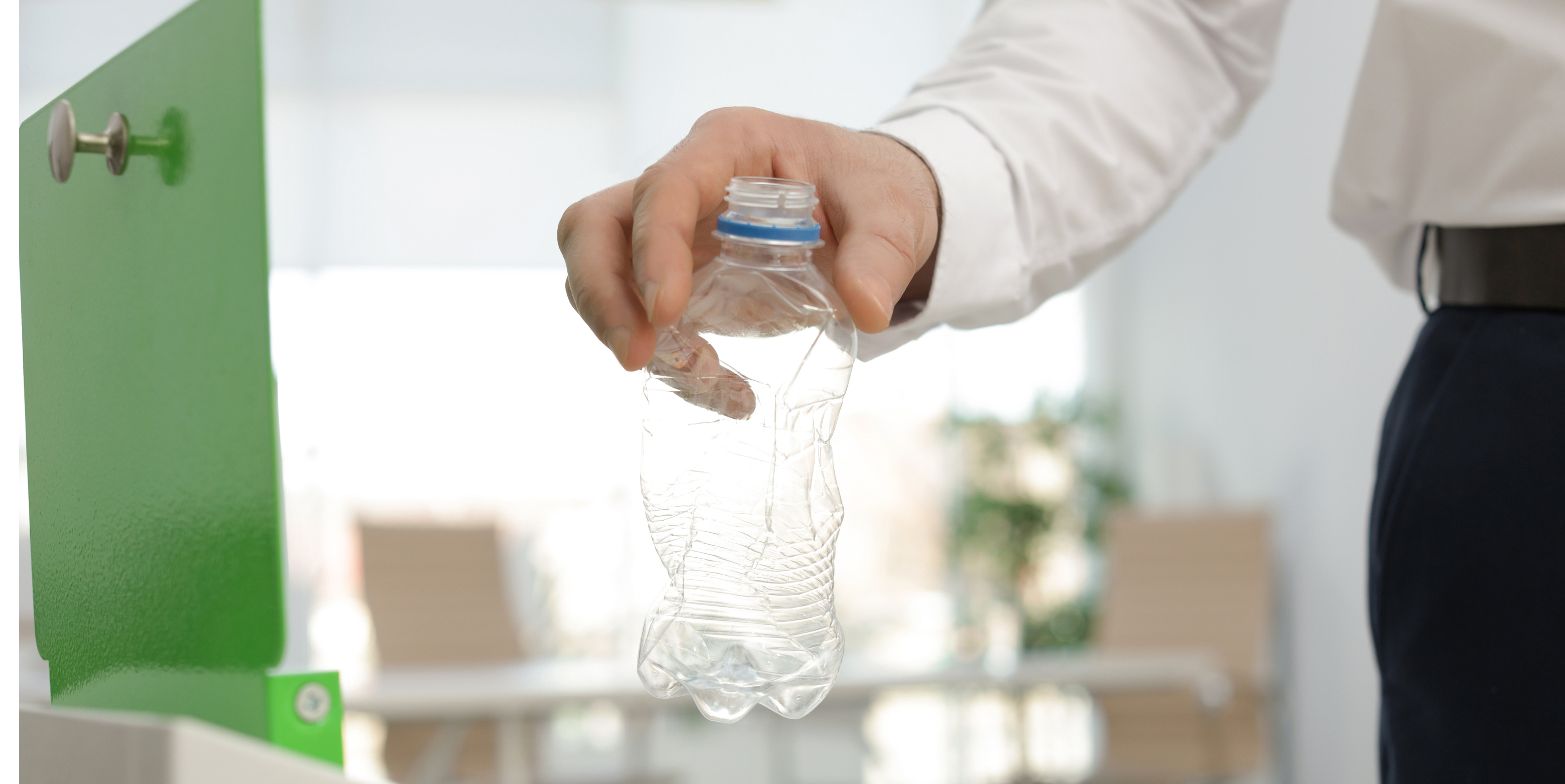 A person in business attire recycling a plastic bottle
