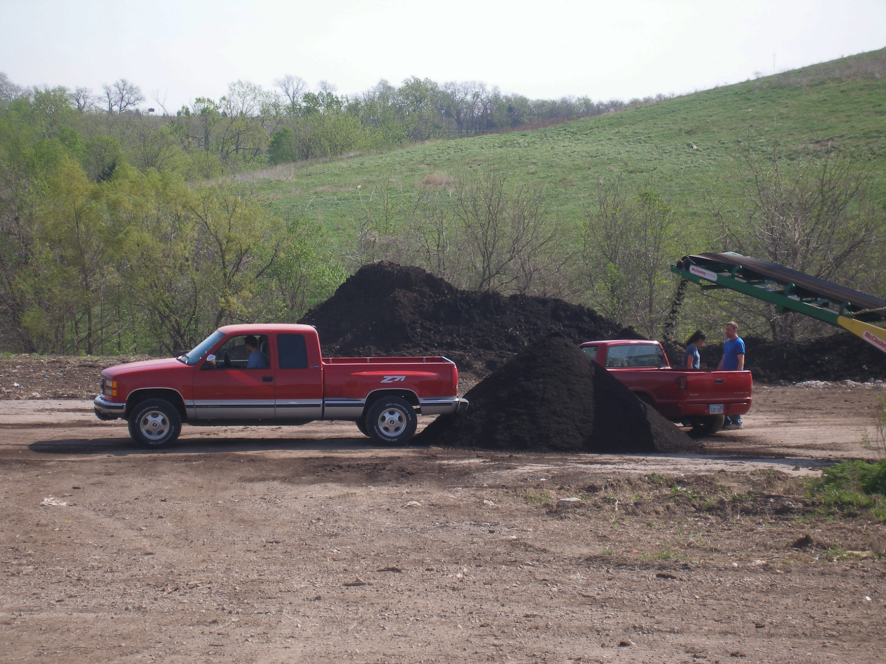 Machines move compost into trucks at a municipal composting facility