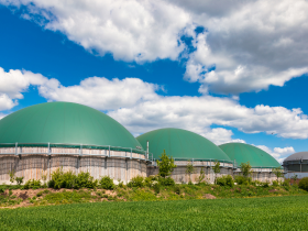 Three domed anaerobic digesters in a field under a blue sky