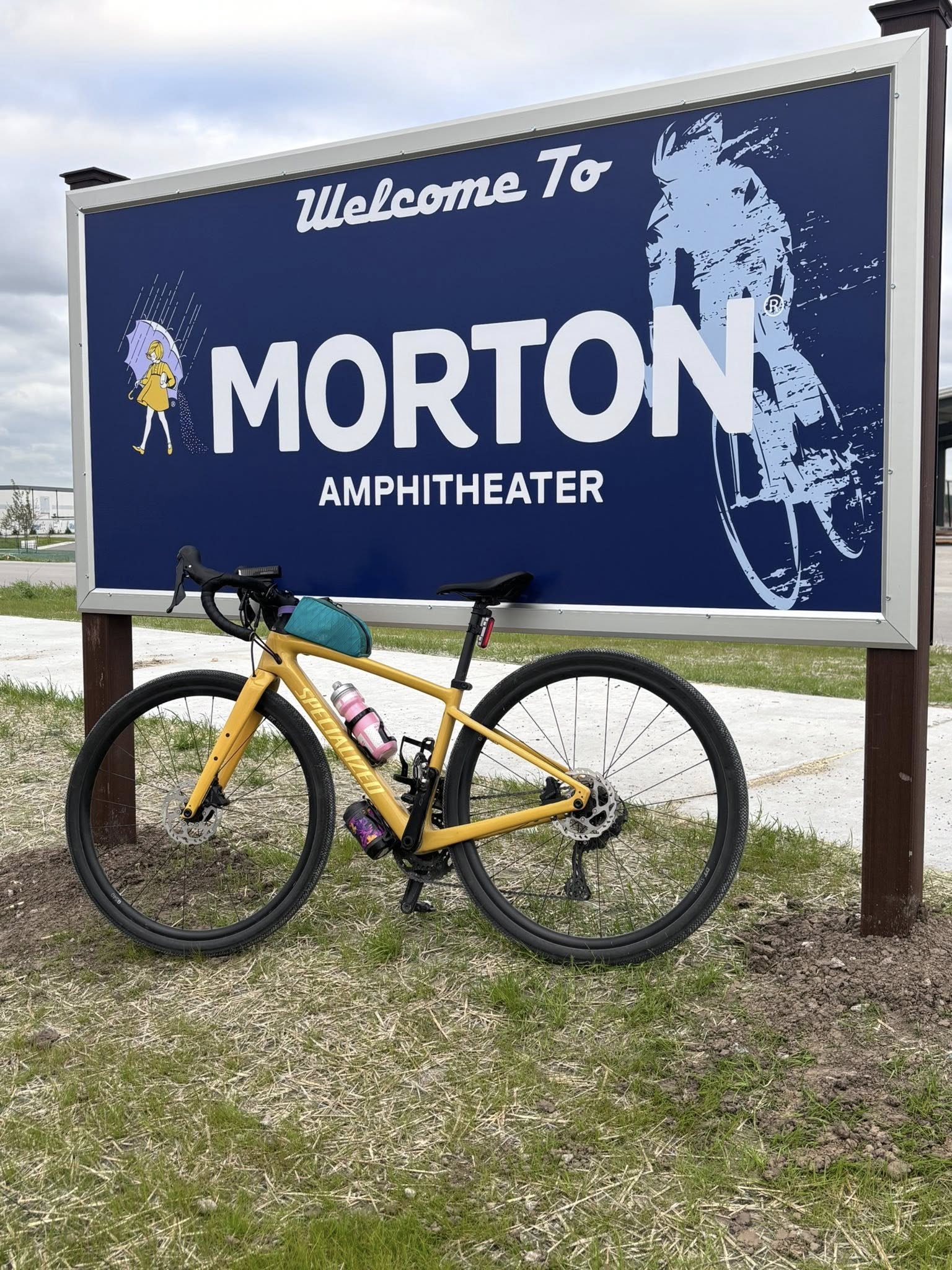 Bike rests against cyclist-themed welcome sign for Morton Amphitheater