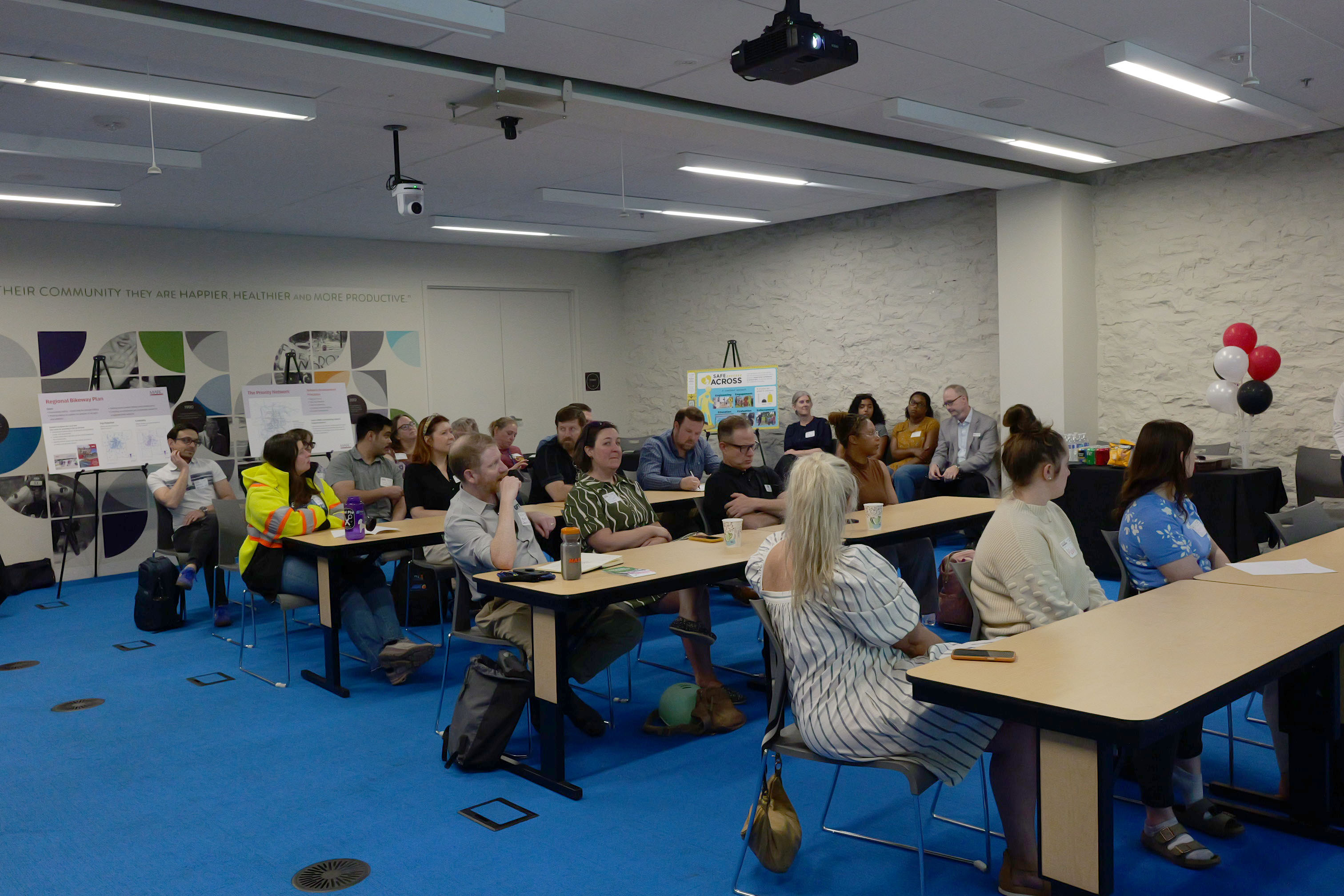 Group of people in a room sitting down listening to a presentation