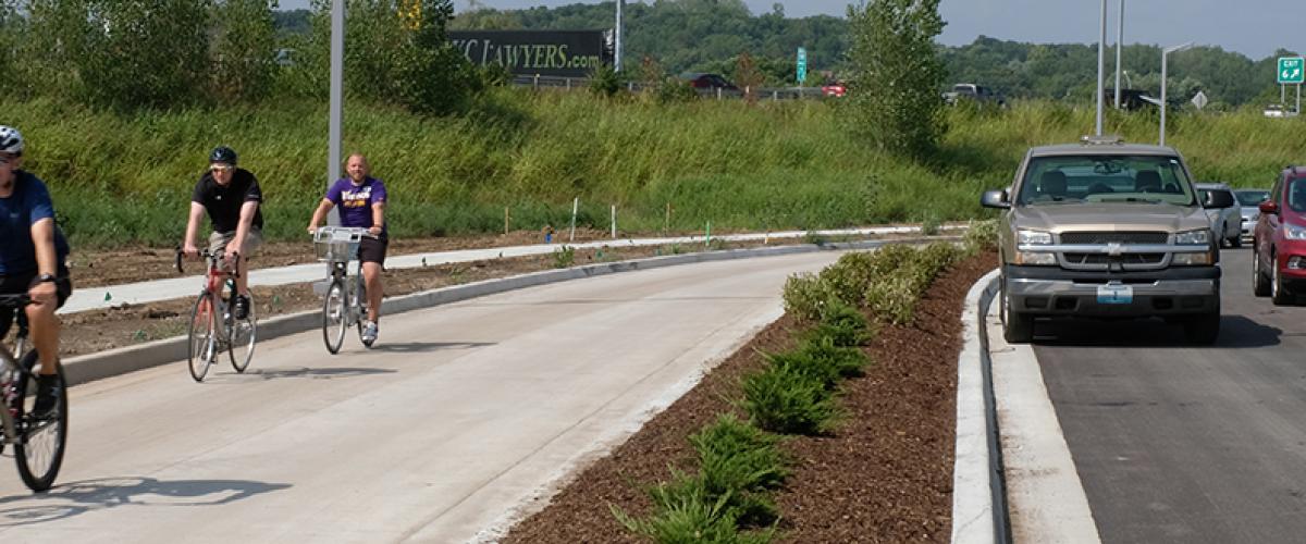 Cyclists riding on a protected bike lane with cars on the road