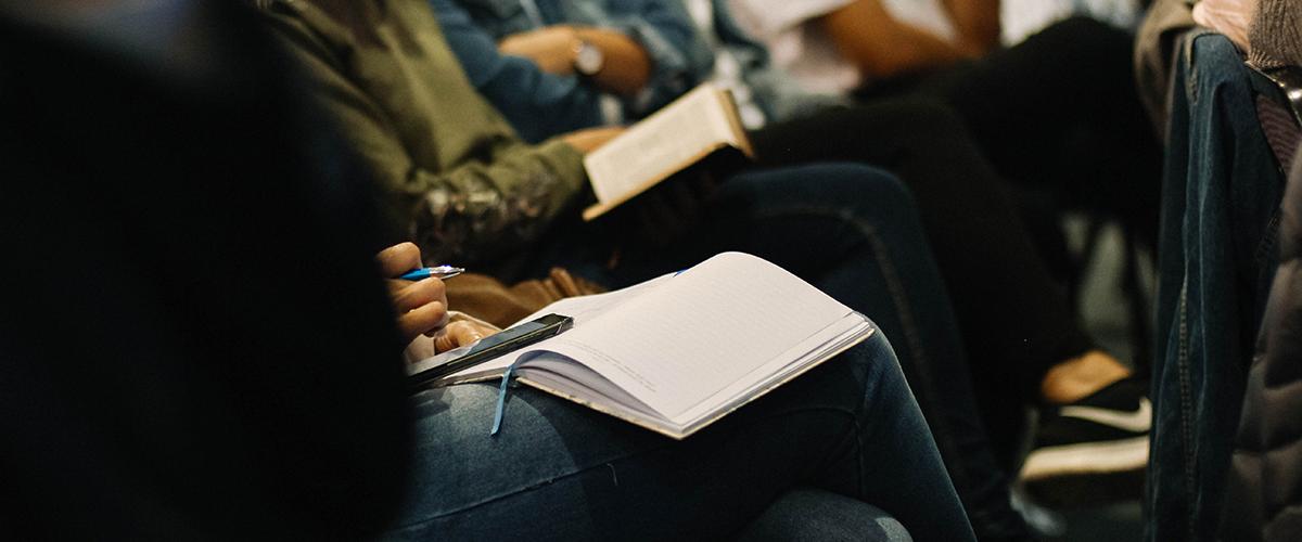 People sitting in a presentation with notebooks