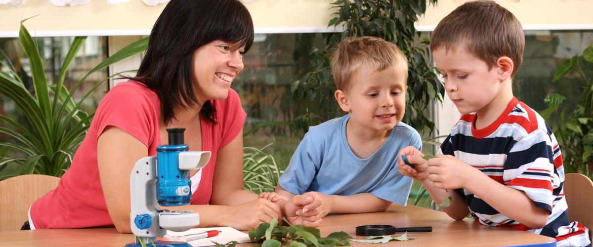 A teacher with two preschool aged boys sitting at a table