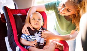 Mother putting child in car seat