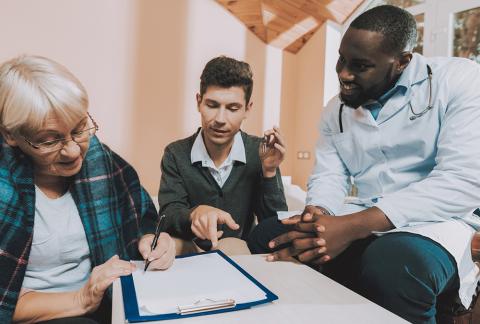 An older adult, caregiver and doctor look over paperwork