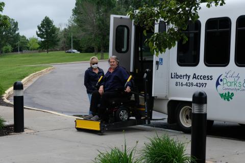 Man in wheelchair being lowered on van lift