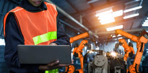 Woman using tablet with manufacturing machines behind