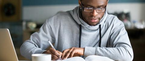 Man taking notes from open book