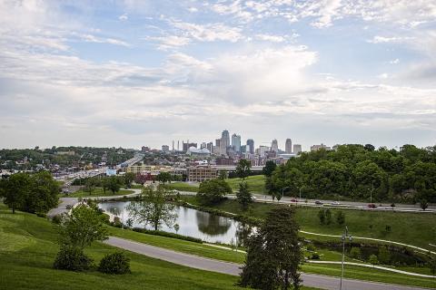 Kansas City skyline from a distance with green park in the foreground and a blue sky