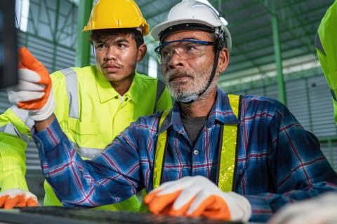 Two men looking at computer in manufacturing facility