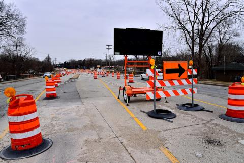 Road under construction with signs and barrels