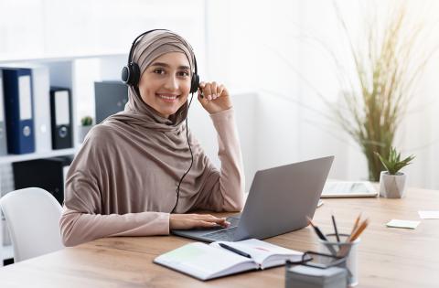 Woman seated in front of a laptop with a headset