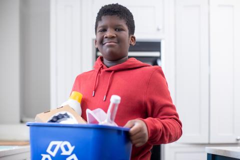 Boy holding a recycling bin with recyclable materials
