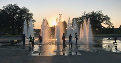 People in silhouette in front of fountain at sunset