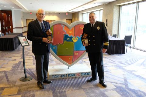 Ed Eilert and Dan Manley with their awards standing in front of the Parade of Hearts art project