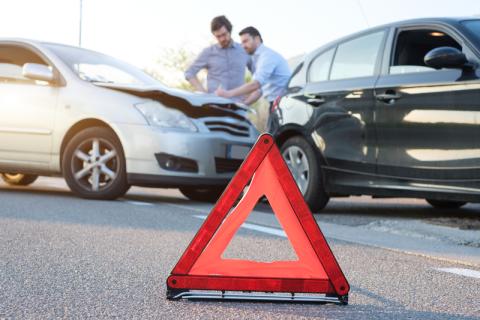 two men assessing damage from car crash