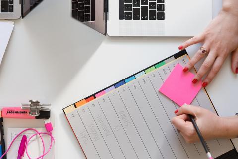 A person writing on a note in a project planning notebook