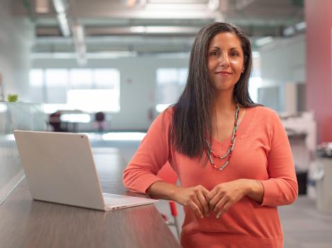 A woman standing in an office near a laptop