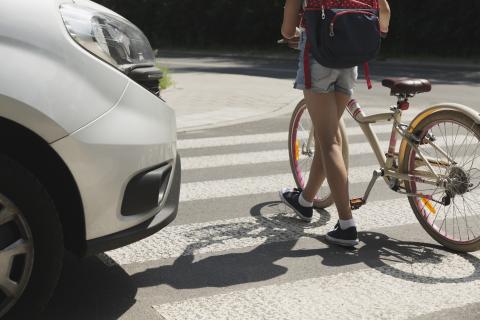 Girl with bike on crosswalk passing a stopped car 