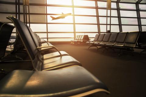 Empty airport terminal with airplane flying in the window