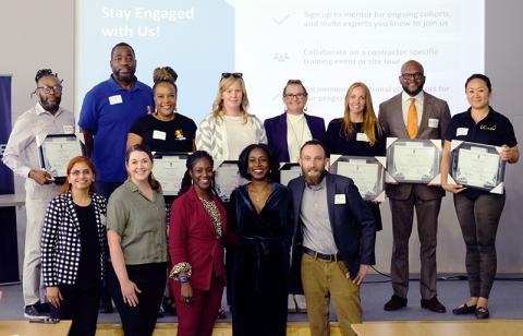 Graduating cohort of Rising Trades accelerator program stand with completion certificates alongside program leaders