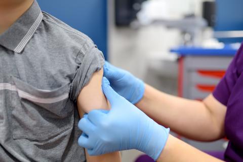 A medical professional massaging a child's arm after a vaccination