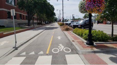 Kansas Avenue intersection showing new streetscape, bike sharrows, cross walk and road-narrowing bumpouts with flower planters