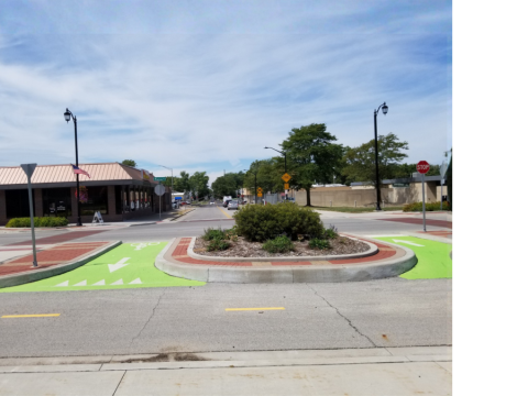 Bright green painted ingress and egress connectors linking separated bicycle lanes to the street