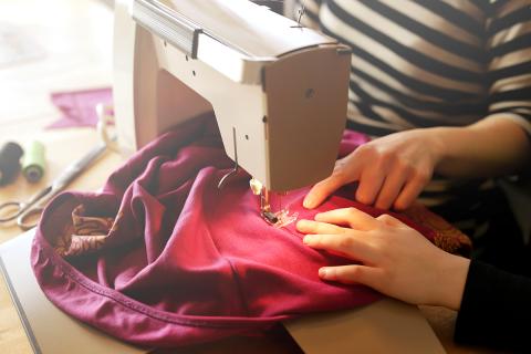 A person demonstrating how to use a sewing machine to someone else