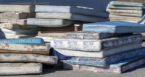 A pile of mattresses outside awaiting recycling