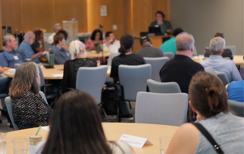 A packed room of attendees listening to a presentation