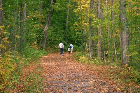A family walks on a trail in early autumn