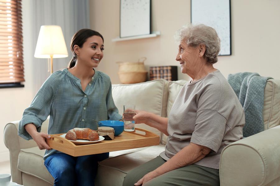 Caregiver providing lunch for older adult