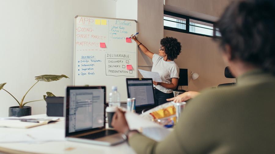 Woman writing on a whiteboard in front of a group