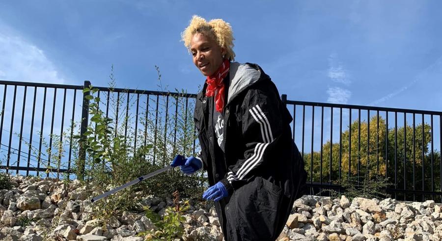 Volunteer with grabber approaches litter from a high angle along a rocky trail