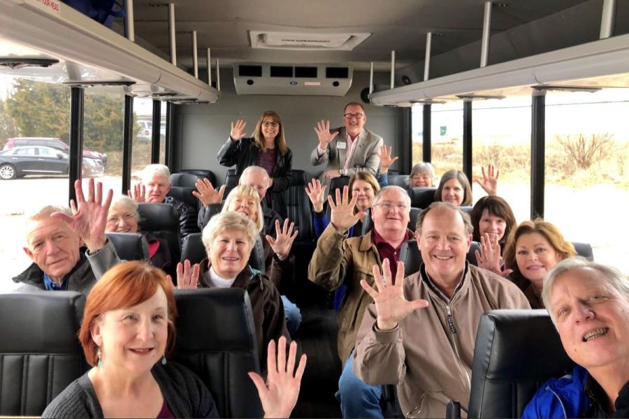 Older adults smiling and waving in a Bus