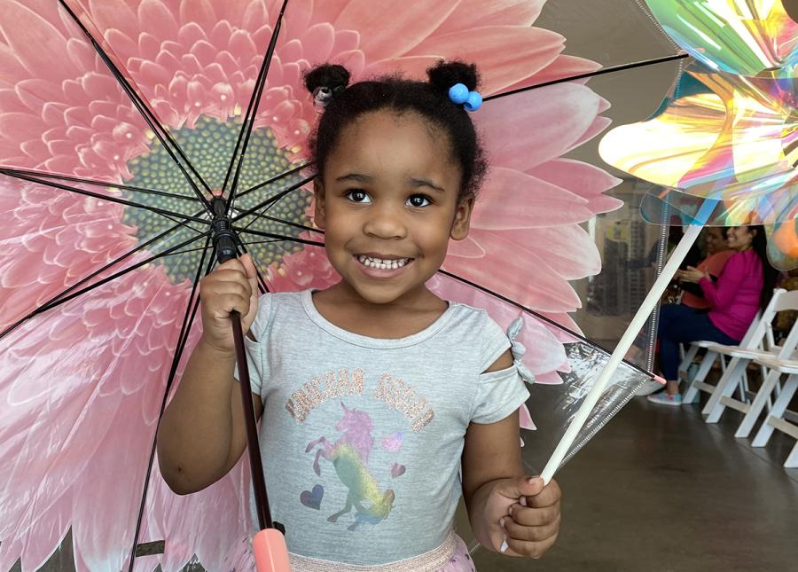 A smiling young girl holding a flower umbrella