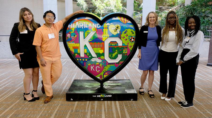 Five summer interns stand next to a heart-shaped sculpture