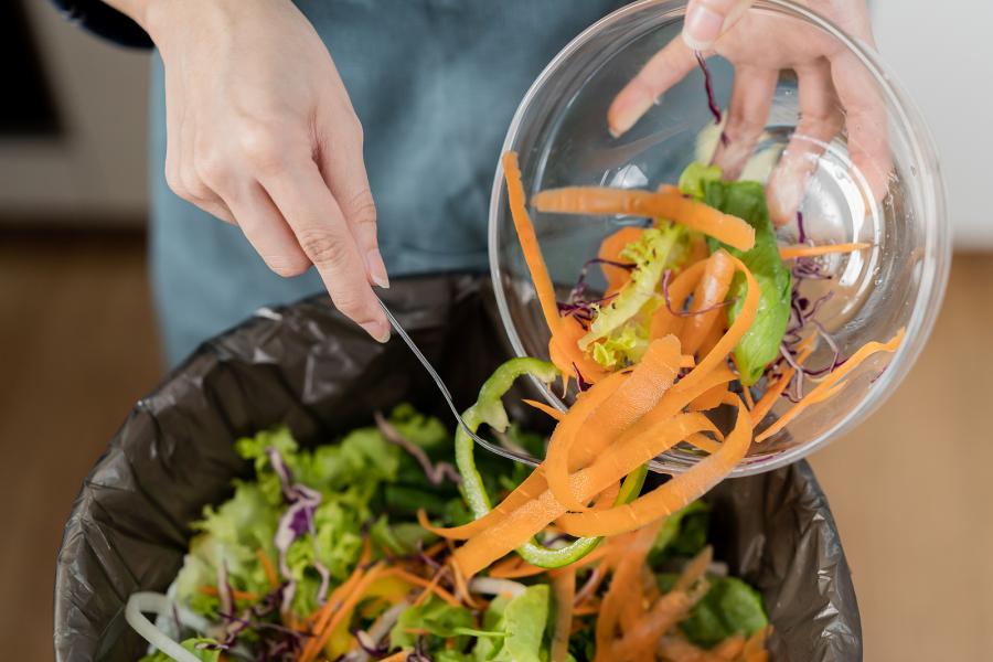 A person empties food scraps into a kitchen compost bin