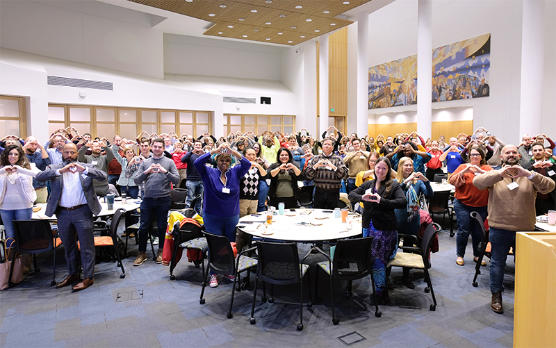 Crowd gathered at climate planning event showing support by making heart symbols with their hands