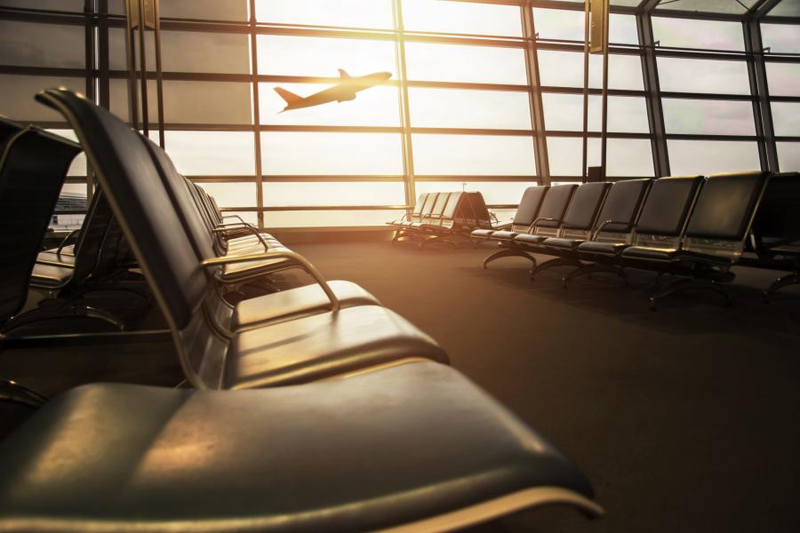 Empty airport terminal with airplane flying in the window
