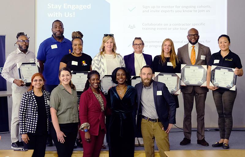 Graduating cohort of Rising Trades accelerator program stand with completion certificates alongside program leaders