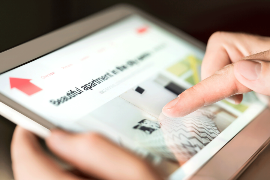 A person holds a tablet that displays a rental website. 