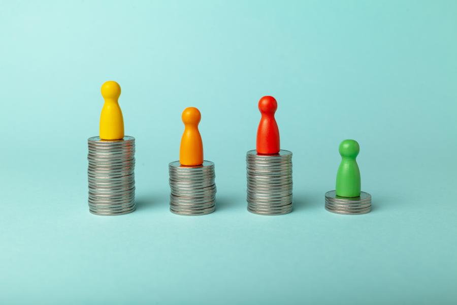 Four different colored game pieces on stacks of coins of varying height.